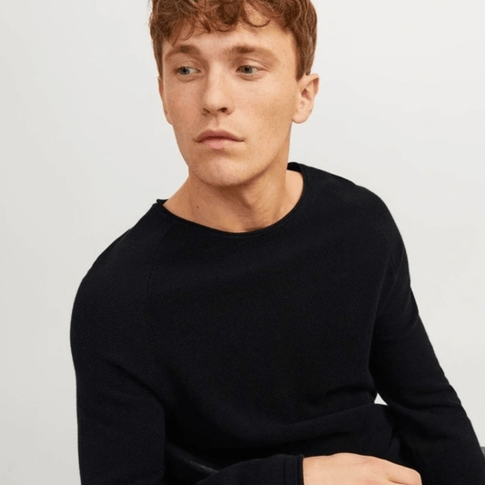 Man wearing a black sweater against a light gray background. Jack & Jones Hill cotton knit crew neck pullover in black available from Stewart's Menswear in Mullumbimby.