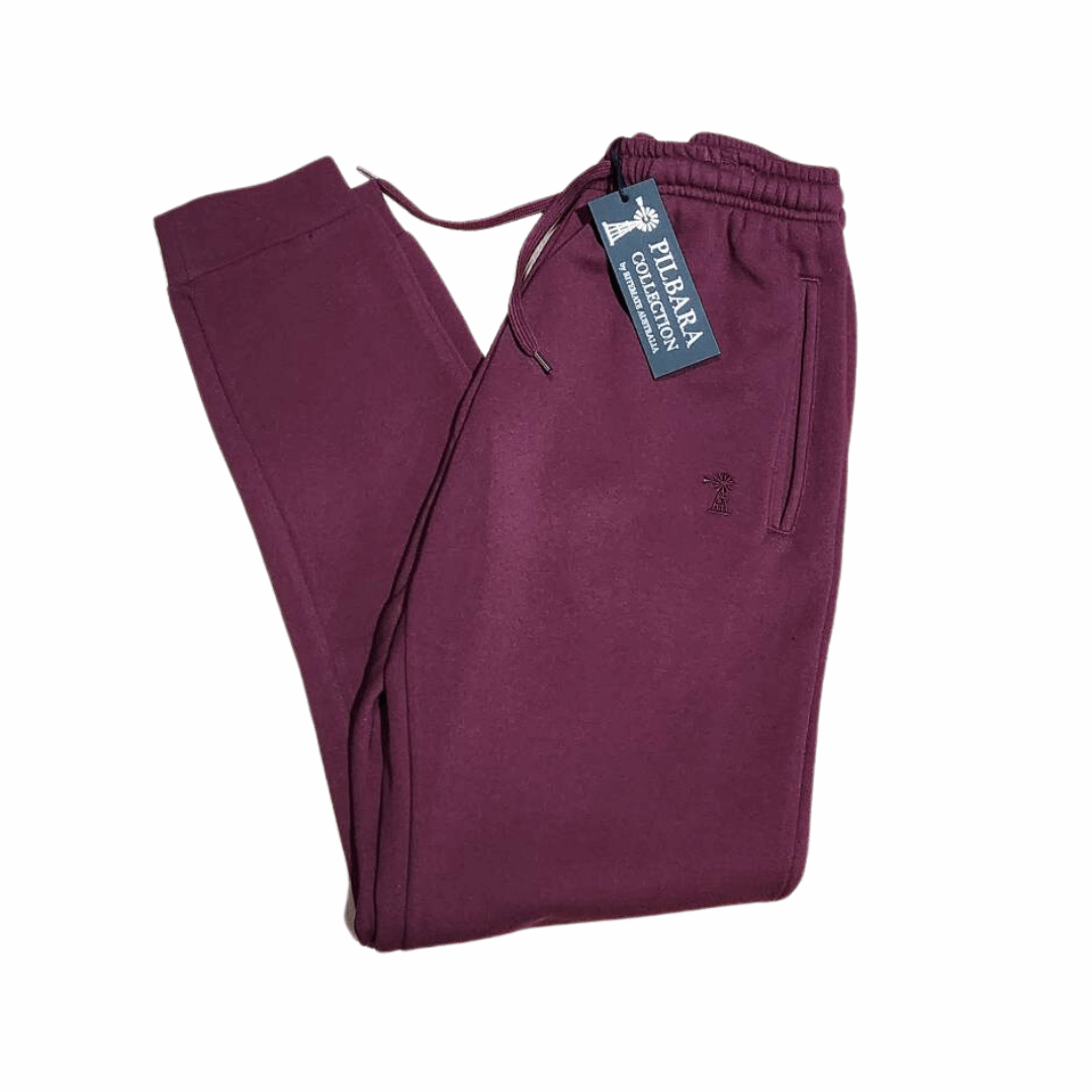Stewart's Menswear Mullumbimby Pilbara Unisex fleece track pant - Maroon colour. Made from a blend of 80% cotton and 20% polyester fleece, these track pants provide both warmth and durability, weighing in at a comfortable 310gsm.   The track pants feature the Pilbara "Windmill" embroidery and a ribbed cuff. The elastic waistband and waist drawcord ensure a perfect  fit for all body types.