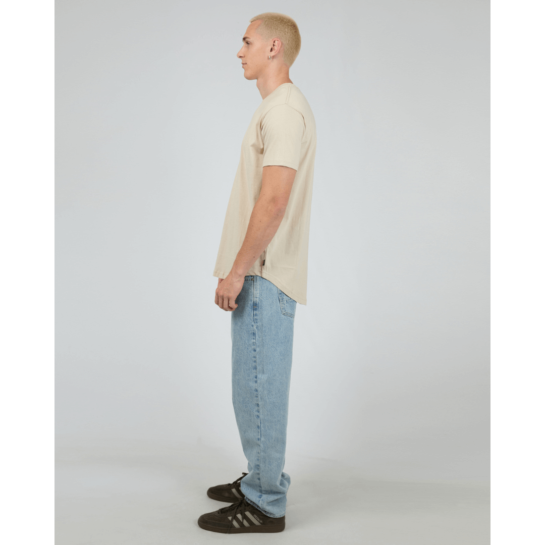Stewart's Menswear, Mullumbimby. Product photo of model wearing Silent Theory Solid Tail Tee. Side VIew. Colour is Tan.