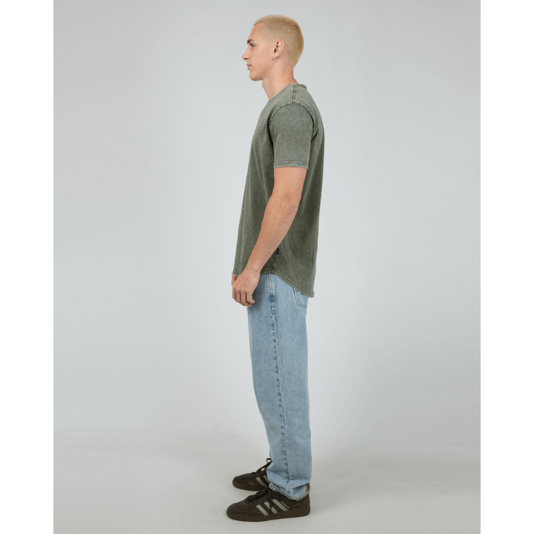 Stewarts Menswear, Mullumbimby. Photo shows model wearing  khaki coloured Silent Theory Tail Tee, side view.