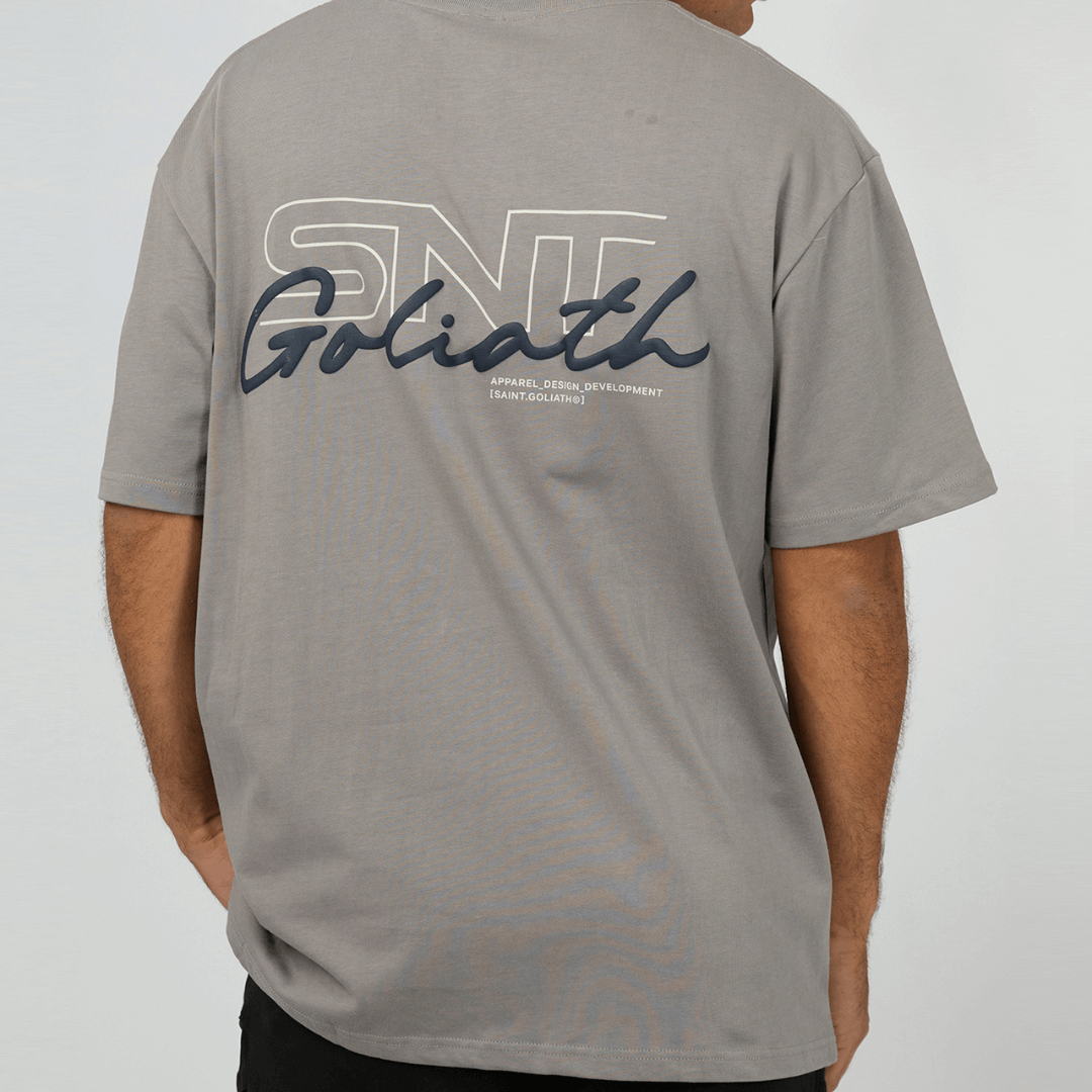 Stewart's Menswear mullumbimby. St Goliath Link Script Tee. Photo shows back view of model wearing St Goliath Link Script Tee, Smoke (light grey) colour with large logo on back.