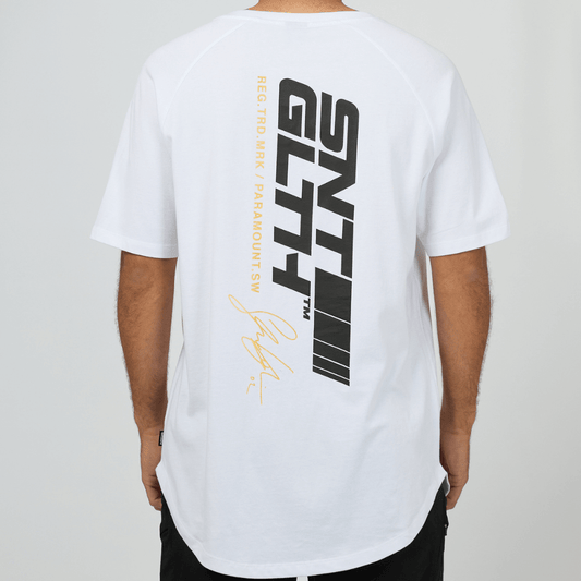 Stewarts Menswear, Mullumbimby. Photo shows model wearing St Goliath Pace Raglan Tee, back view. Colour is white with black and Gold foil print down spine.