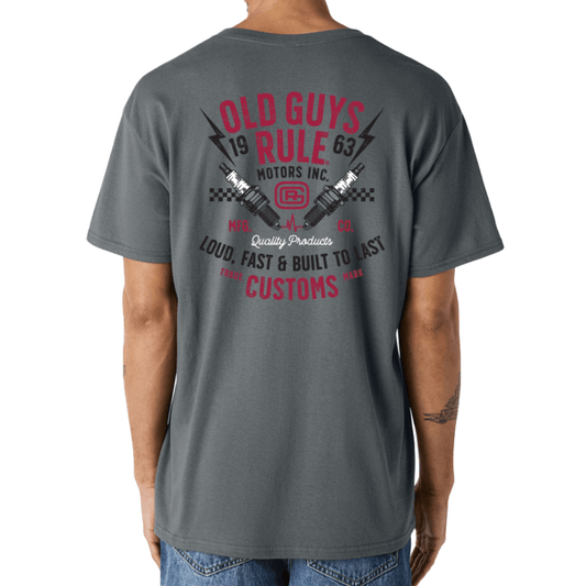 Stewart's Menswear, Mullumbimby. Photo shows model wearing Old Guys Garage T-shirt, back view. Colour is charcoal with black, red and white larg print on back: Old Guys Rule Motors Inc. Loud, fast and built to last.