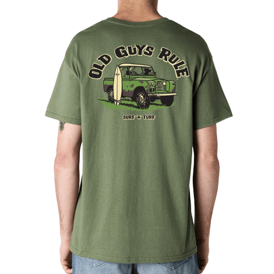 Stewart's Menswear, Mullumbimby. Old Guys Rule Surf & Turf T-shirt. Photo shows model wearing Old Guys Rule T-shirt, back view. Colour is military green with graphic of an old jeep with a surfboard leaning against it.