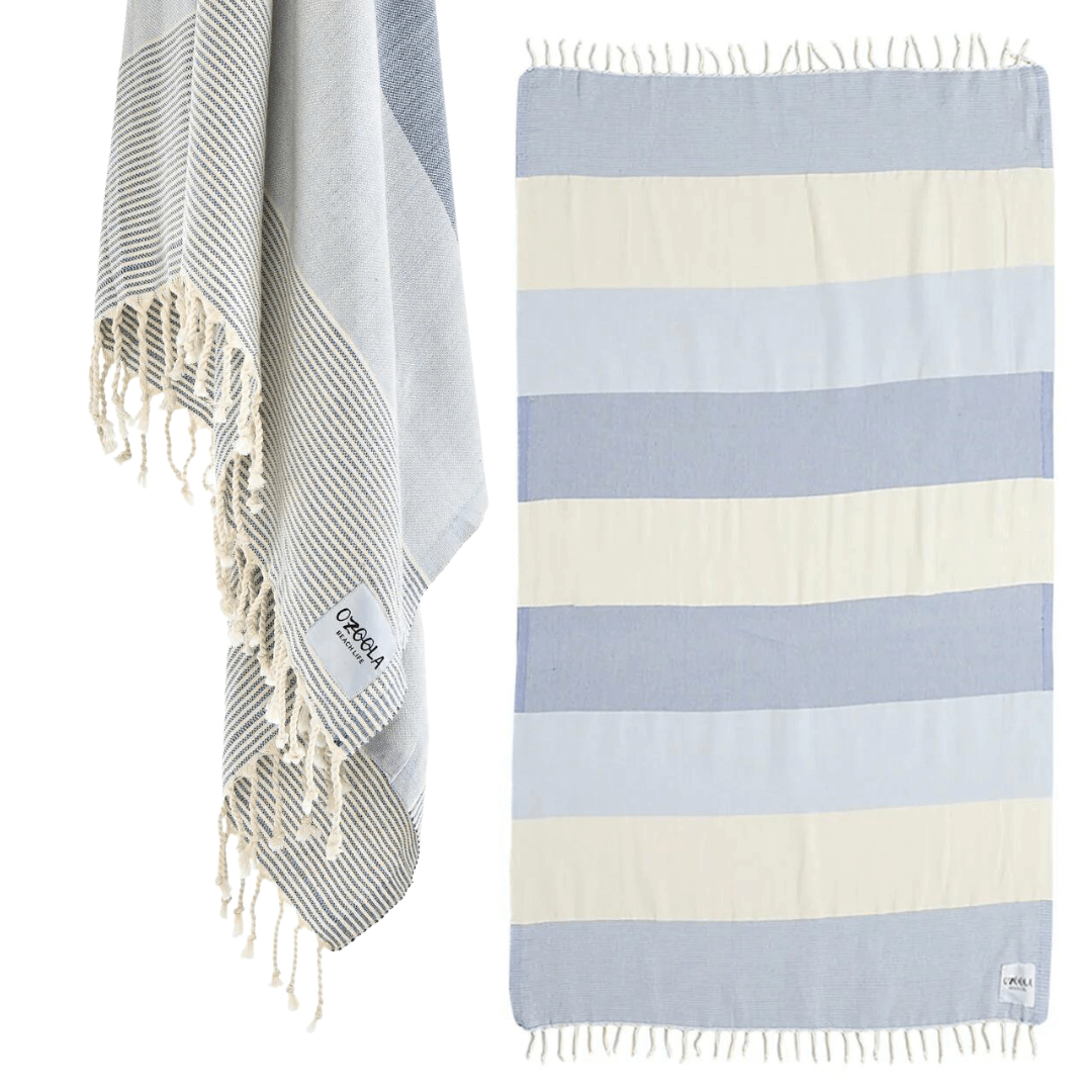 Stewarts Menswear Ozoola Johnny Towel. The Johnny Towel is made from 100% Turkish Cotton which is super absorbent and fast drying.  Sized at 180 x 100cm with knotted fringing at each end. Ideal for endless beach days, and lazy pool days.  Soft and light, it is perfect for travelling and it can also be used as a sarong.  Colour is Natural Blue with wide stripes of constrast colours.