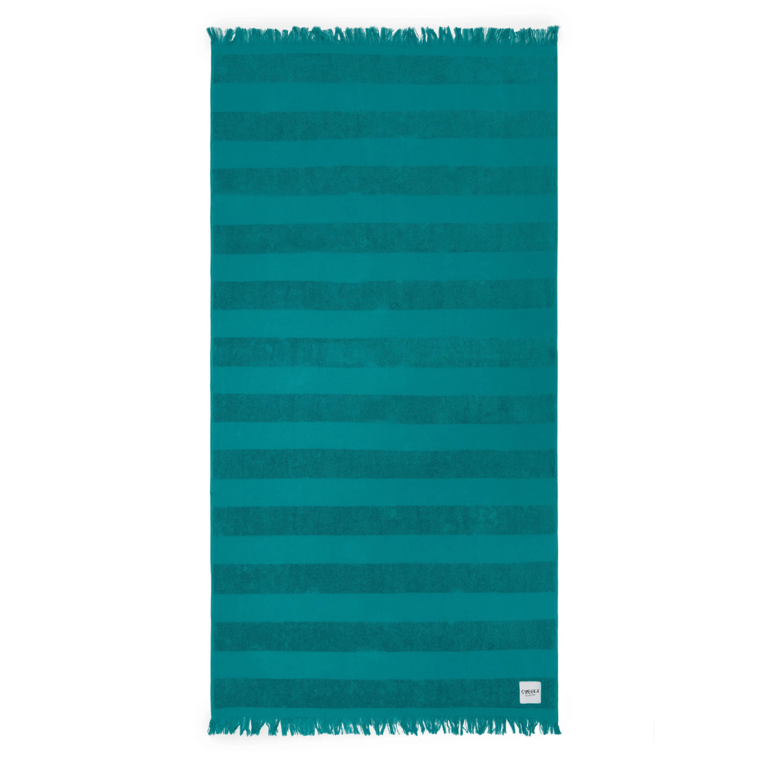 Stewarts Menswear Ozoola Pool to Beach towel.The newest addition to the OZoola Beach Towels range is the Pool to Beach towel.  Perfect for endless beach days, lazy pool days, and travelling. Soft and light, this towel features a combination the very popular Turkish Cotton towels with the addition of terry stripes to keep you dry in style. Colour is Cove (a bright teal colour). 