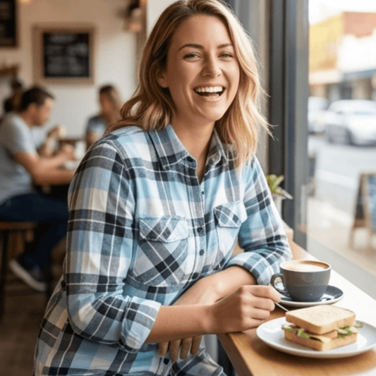 Lady sitting in a cafe wearing Pilbara collection ladies flannelette shirt in cerulean/grey/white available at Stewart's Menswear in Mullumbimby