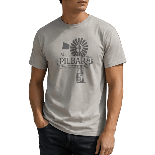 A man wearing a moonbeam coloured crewneck t-shirt with a vintage-style windmill graphic and the text 'The PILBARA Co.' on the chest, paired with dark jeans against a plain white background.