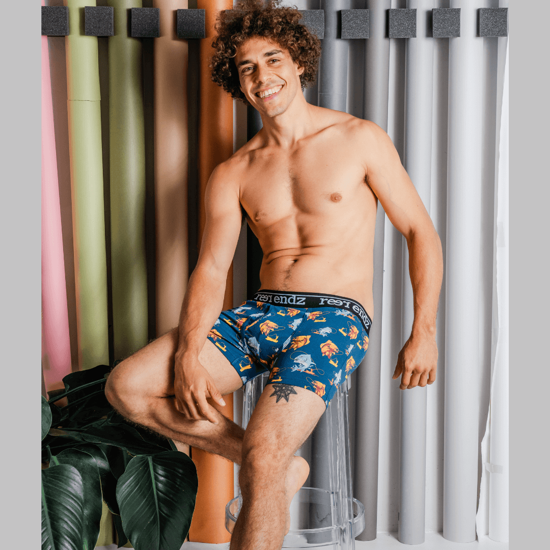 Stewarts Menswear Reer endz organic Cotton underwear. Hooked is a rich blue coloured men's trunk with a man in a fishing boat catching a fish printed all over. Photo is of model wearing Hooked men's underwear.