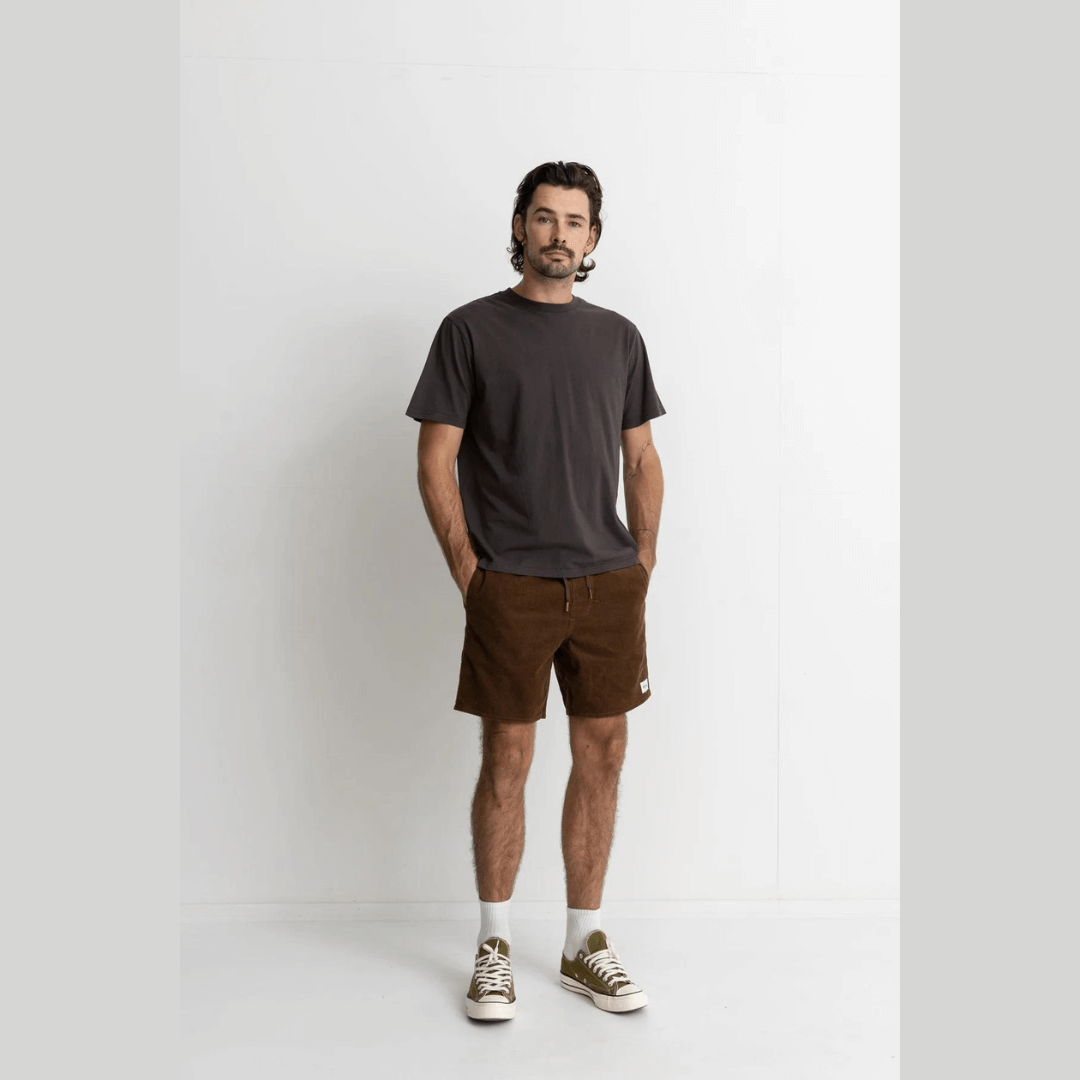 Stewarts Menswear Rhythm classic cord jam. Shorter length, elastic waist with drawcord. Rhythm labels on back and front. Colour is Chocolate. Photo shows model wearing an outfit featuring chocolate coloured classic cord jam shorts.