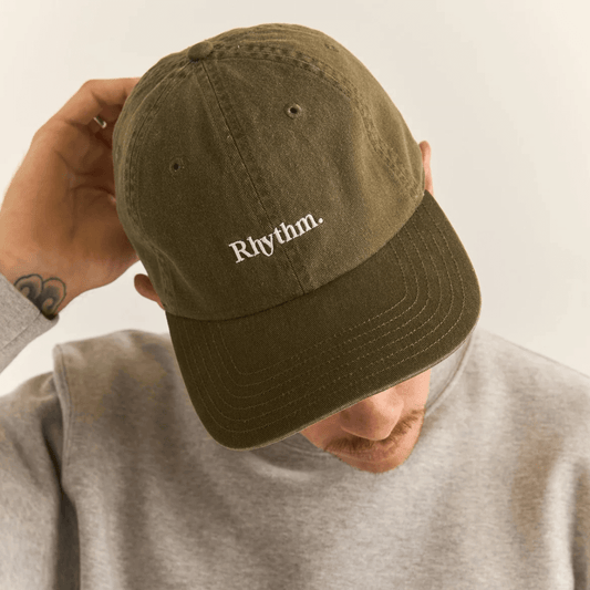 Stewarts Menswear Rhythm Livin Essential Cap. A Classic 6 panel curved visor cap. Colour is Fatigue (brownish Khaki colour) with white embroidered Rhythm Logo.