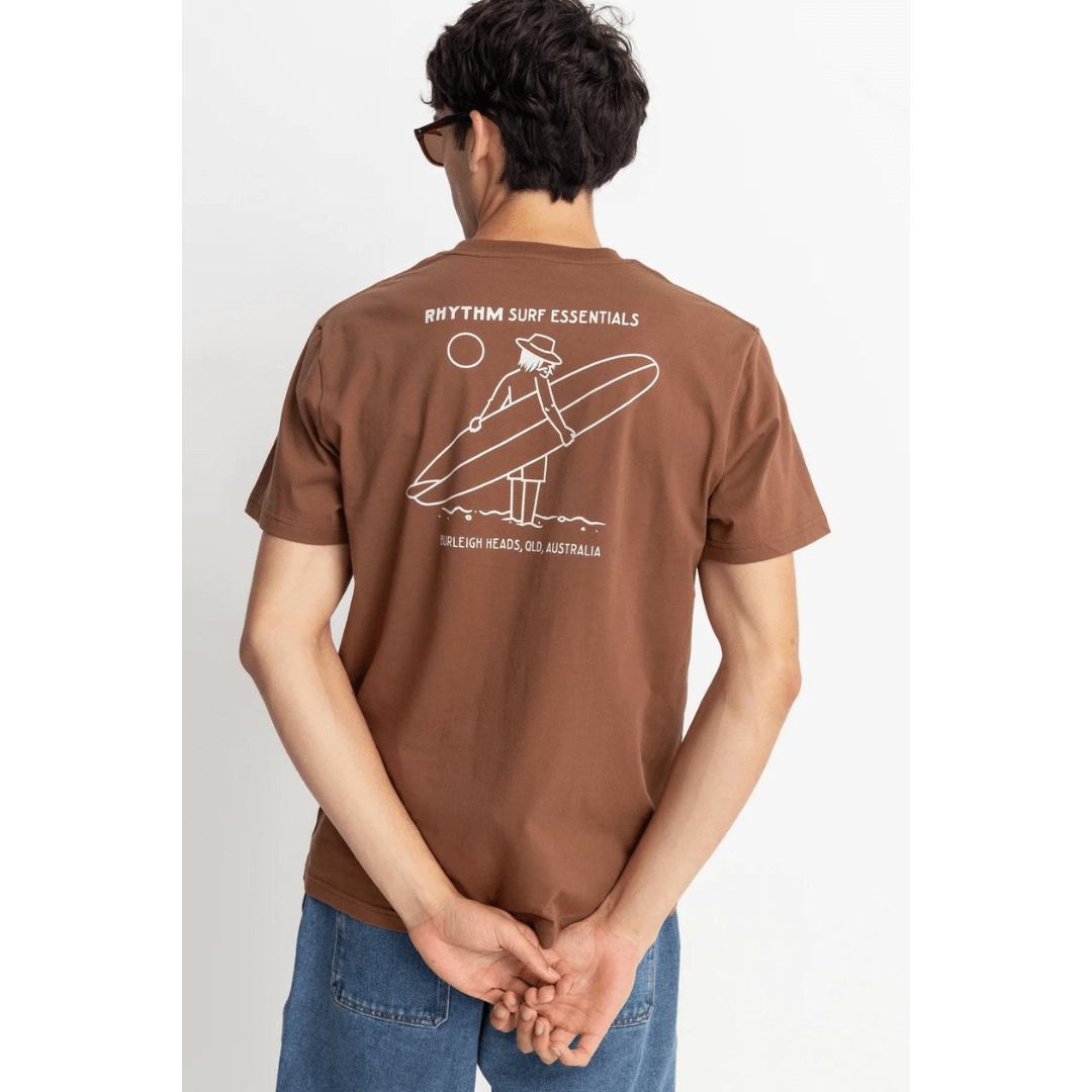 Stewarts Menswear Rhythm Livin Lull T-shirt. Colour is chocolate. Image shows back of Tee shirt with screen print of man carrying a surfboard with the text: Rhythm Surf Essentials Burleigh Heads, QLD Australia