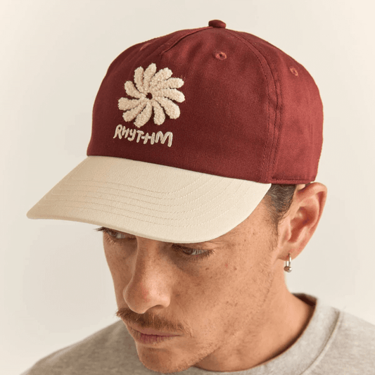 Stewarts Menswear Rhythm Livin Sun Cap. a 5 panel cap with embroidered Rhythm logo and artwork. Cap colour is moroccan red (a rusty red colour) with a cream coloured visor and embroidery.