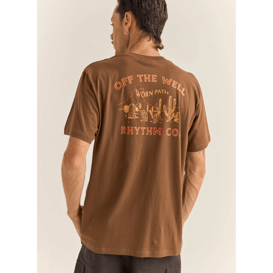 Stewarts Menswear Rhythm Livin Worn Path Tee. A signature print of cacti with celebrates life "Off The Well". Photo shows model wearing Worn Path tee back view. Colour is Chocolate (vintage wash).