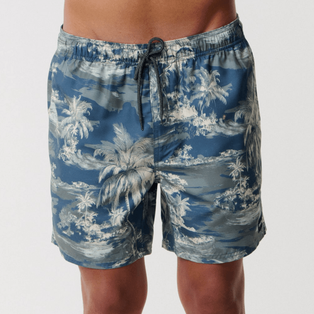 Stewarts Menswear Rip Curl Dreamers Volley Short. Colour is pine, a blue base with pine green island/palm tree print all over. Photo shows front view of model wearing Rip Curl Dreamers Volley Short available at Stewarts Menswear, Mullumbimby