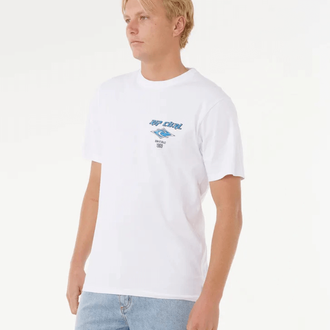 Stewarts Menswear, Mullumbimby. Photo shows model wearing Rip Curl Fade Out Icon Tee, front view. White tee with Blue Rip Curl branding.