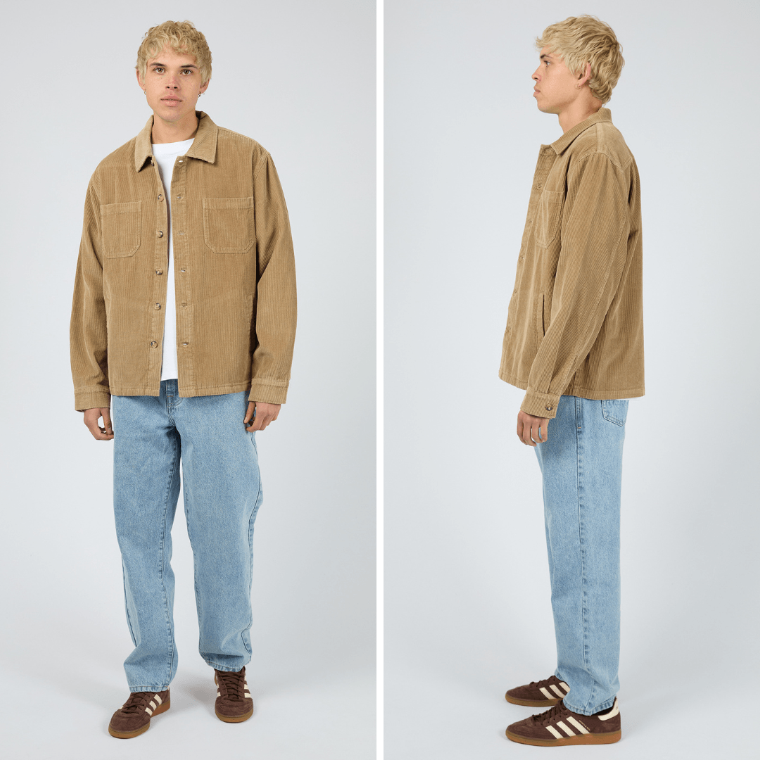 Model wearing a tan coloured corduroy shirt and light blue jeans on a gray background. Silent Theory Jameson Cord Shirt in cotton corduroy available at Stewart’s Menswear Mullumbimby.
