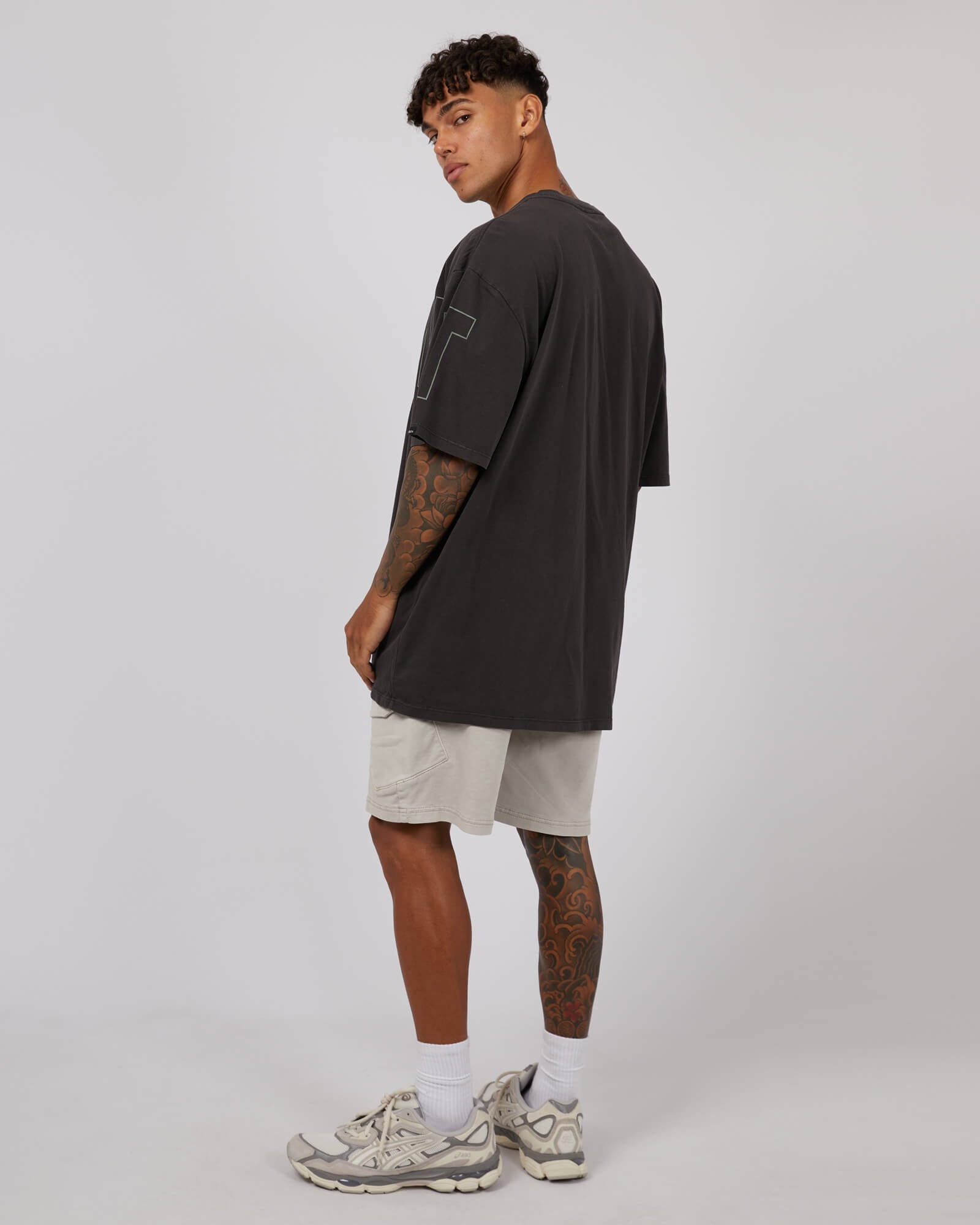 Stewarts Menswear St Goliath Riser Tee. Colour is black. Photo shows model wearing St Goliath Riser Tee, back/side view.