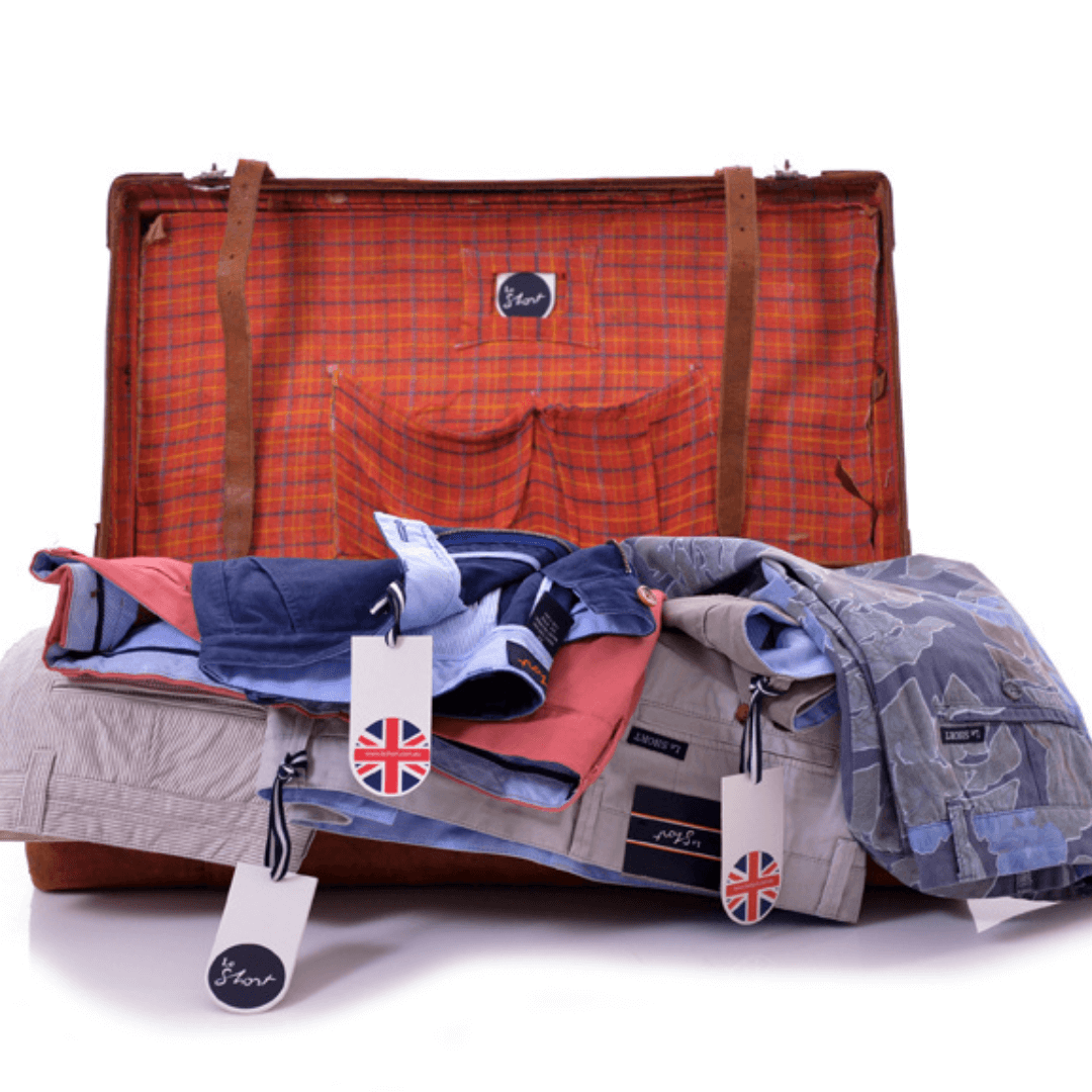 Stewarts Menswear Le Short Stretch Cotton shorts. Lifestyle photo shows a selection of shorts spilling out of a suitcase.