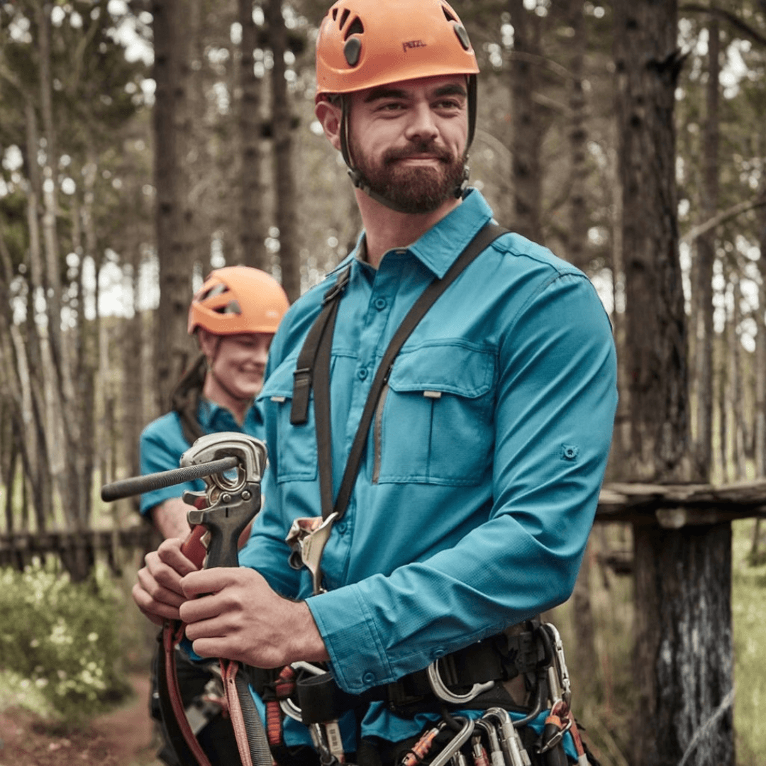 Man wearing the Syzmik Outdoor Long Sleeve Shirt in Diesel outdoors among the trees, available at Stewart's Menswear Mullumbimby.