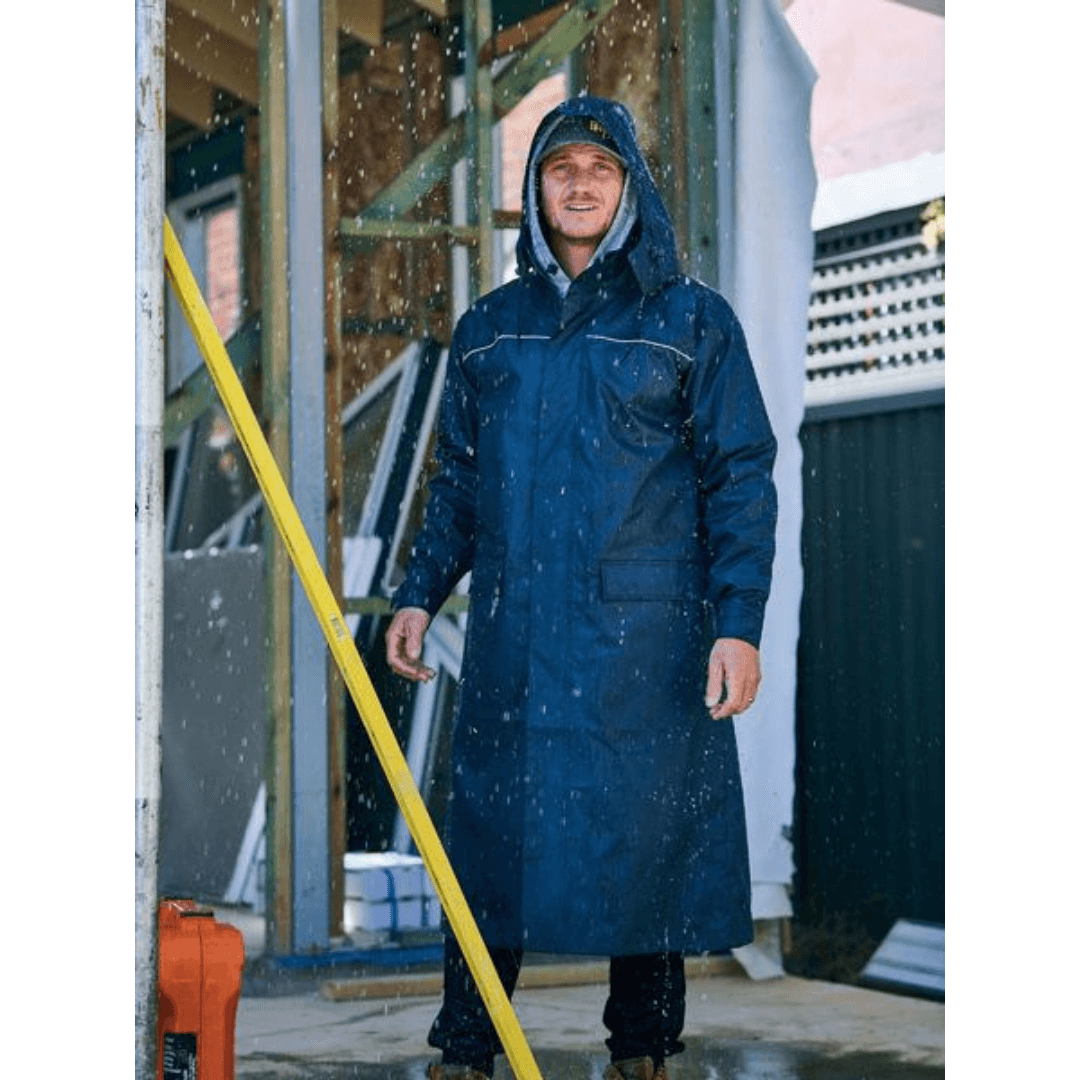 Stewart's Menswear Bisley long raincoat, unisex, navy, Lifestyle photo. Bisley's long raincoat is made with waterproof and non-breathable fabric. A waterproof rating of up to 10,000mm and H20 and seam-sealed construction together with it's long length ensures you will stay dry even in the heaviest rain. This long raincoat is ideal for people who work outdoors. The coat can also be used for hiking, camping, or any other outdoor activity where rain is a possibility.