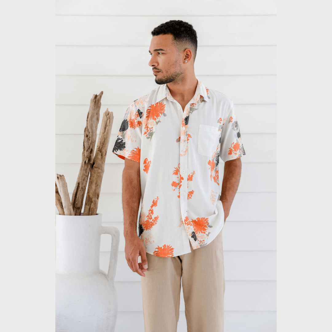 Male Model wearing hemp bamboo floral printed short sleeve shirt. Colour is white with orange/black/grey floral print
