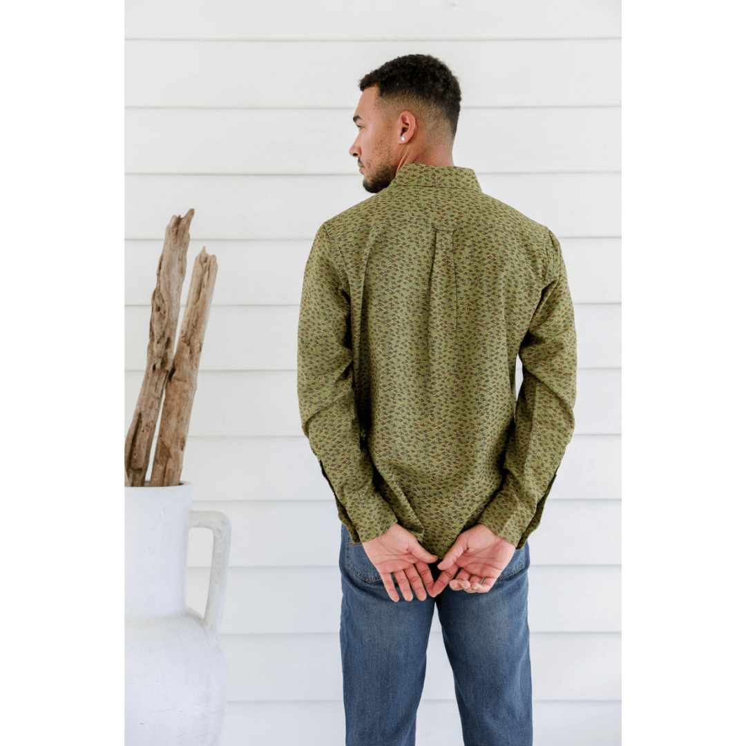 Male model is wearing a Hemp/cotton blend men's long sleeve shirt. Green with brown and mustard dandelion seeds printed all over. Back view.