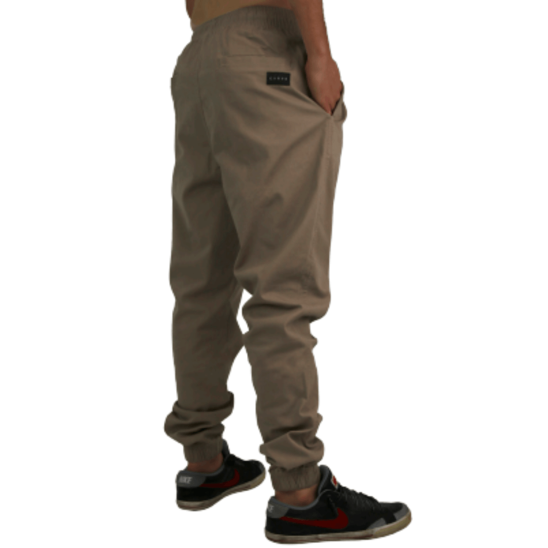 Carve surf brand Ollie is a comfortable regular fit Jogger Pant featuring an elastic waist and ankle. Made with a soft and durable cotton elastane blend, they have a comfortable fit which allows for freedom of  movement and breathability.  You can easily store your essentials like keys, phone, or wallet in the front welt pockets plus a back pocket.   The perfect choice with a tee-shirt or fleece top for casual weekend wear. Colourway is stone. Back/side view